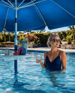 In pool table with umbrella with woman under it.