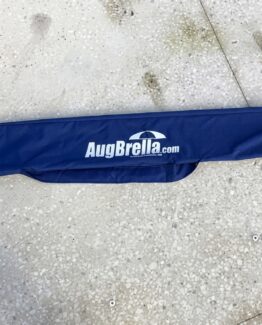 Blue fabric sleeve with the white 'AugBrella.com' logo and umbrella icon laid on a speckled concrete floor, viewed from above.