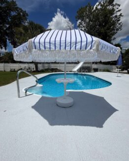 Photo of blue and white umbrella with tassels by a pool