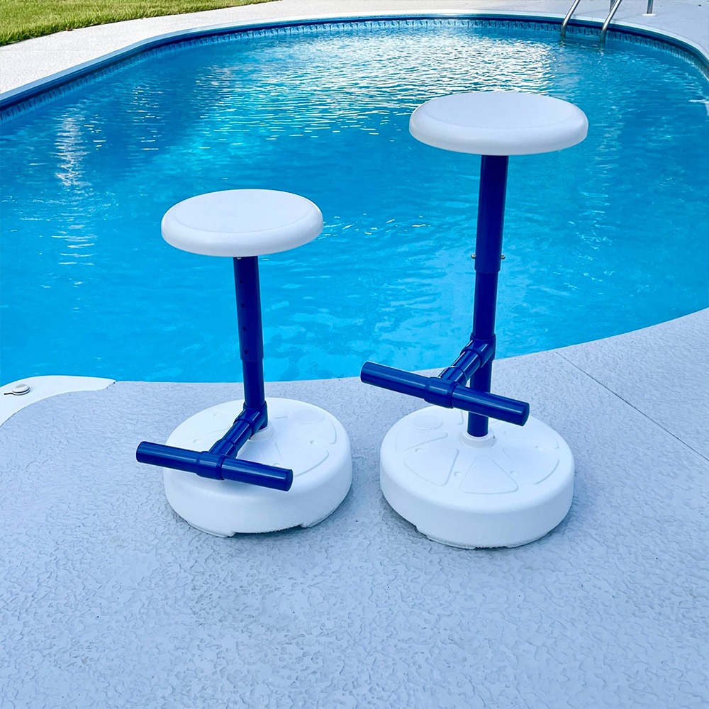Two white round-seated pool stools with blue poles on a concrete pool deck beside a blue swimming pool.