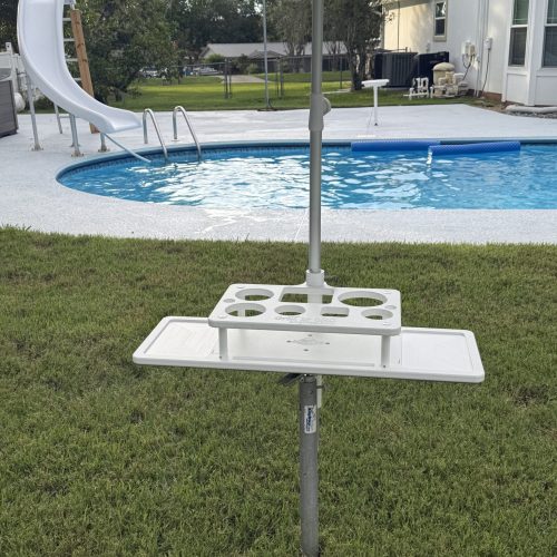Photo of a tabl that holds liquor bottles in the grass near a pool