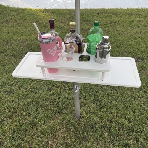 Photo of liquor bottles in the grill and chill table on the grass.