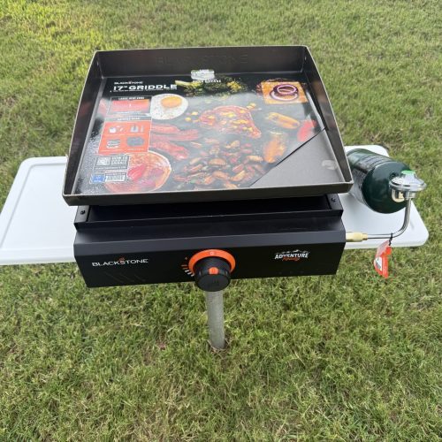 photo of a blackstone rill being used on a grill and chill tabel n the grass on a pole.